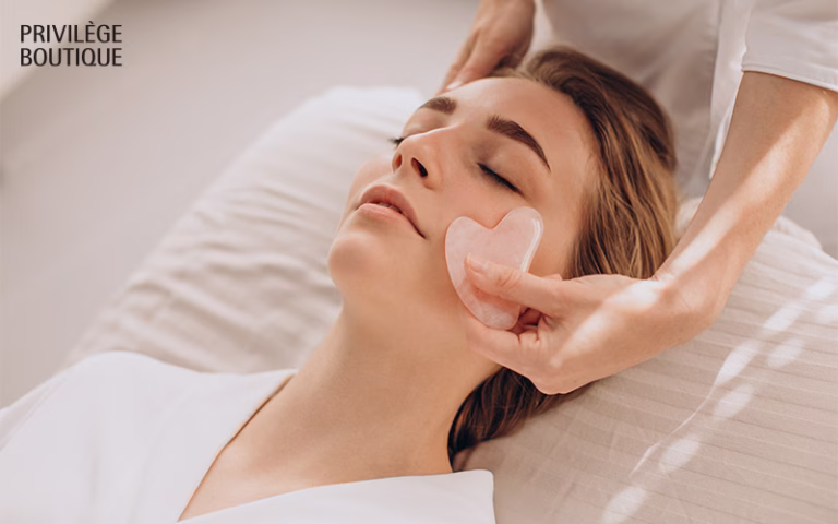Facial massage in spa setting using heart-shaped gua sha tool, with serene lighting and white attire.