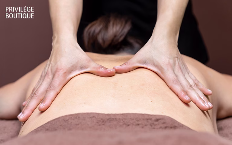 Hands of a massage therapist performing a back massage on a client lying on a treatment table.